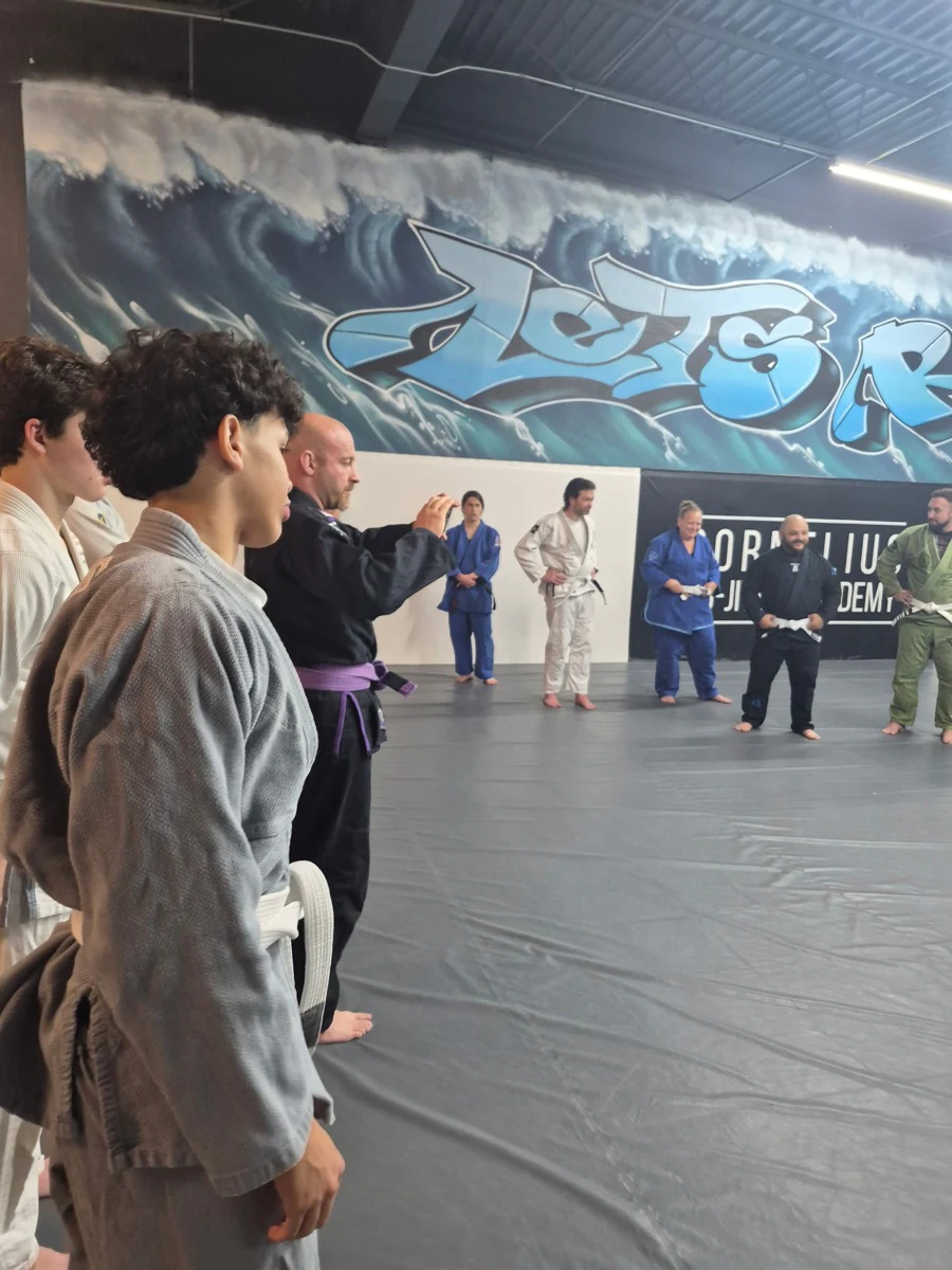 Students in gis gathered in a circle on the academy mats