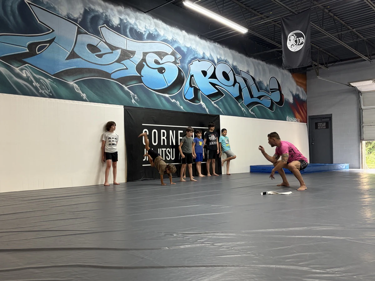 A coach watching a child practice movement while other kids wait their turn