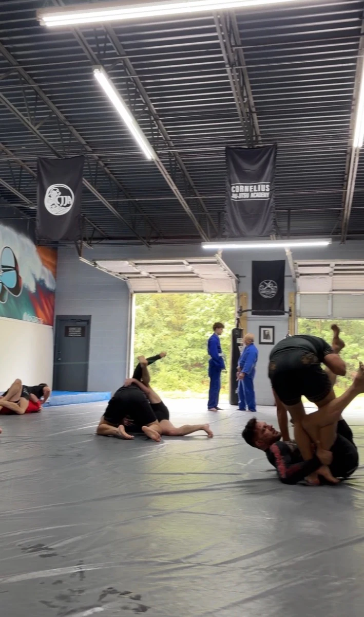 Several pairs sharing Gi and No-Gi rounds on the academy mats