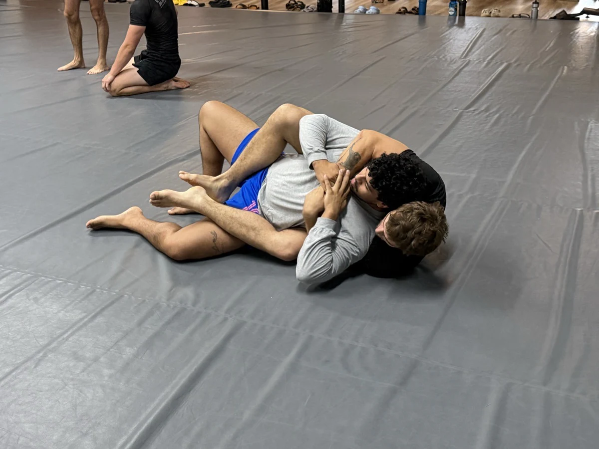 Two partners practicing a no-gi ground position while others watch