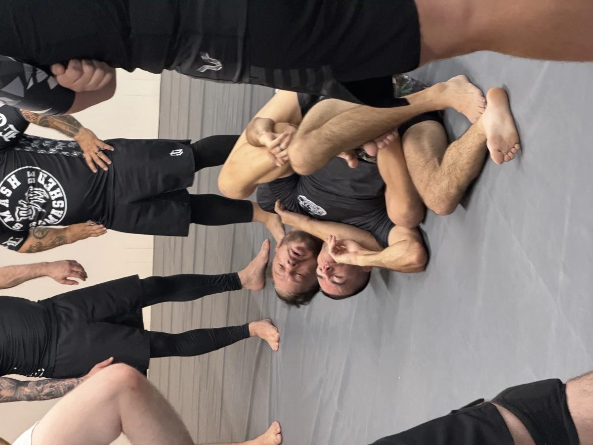 Training partners demonstrating a ground position to a group of students