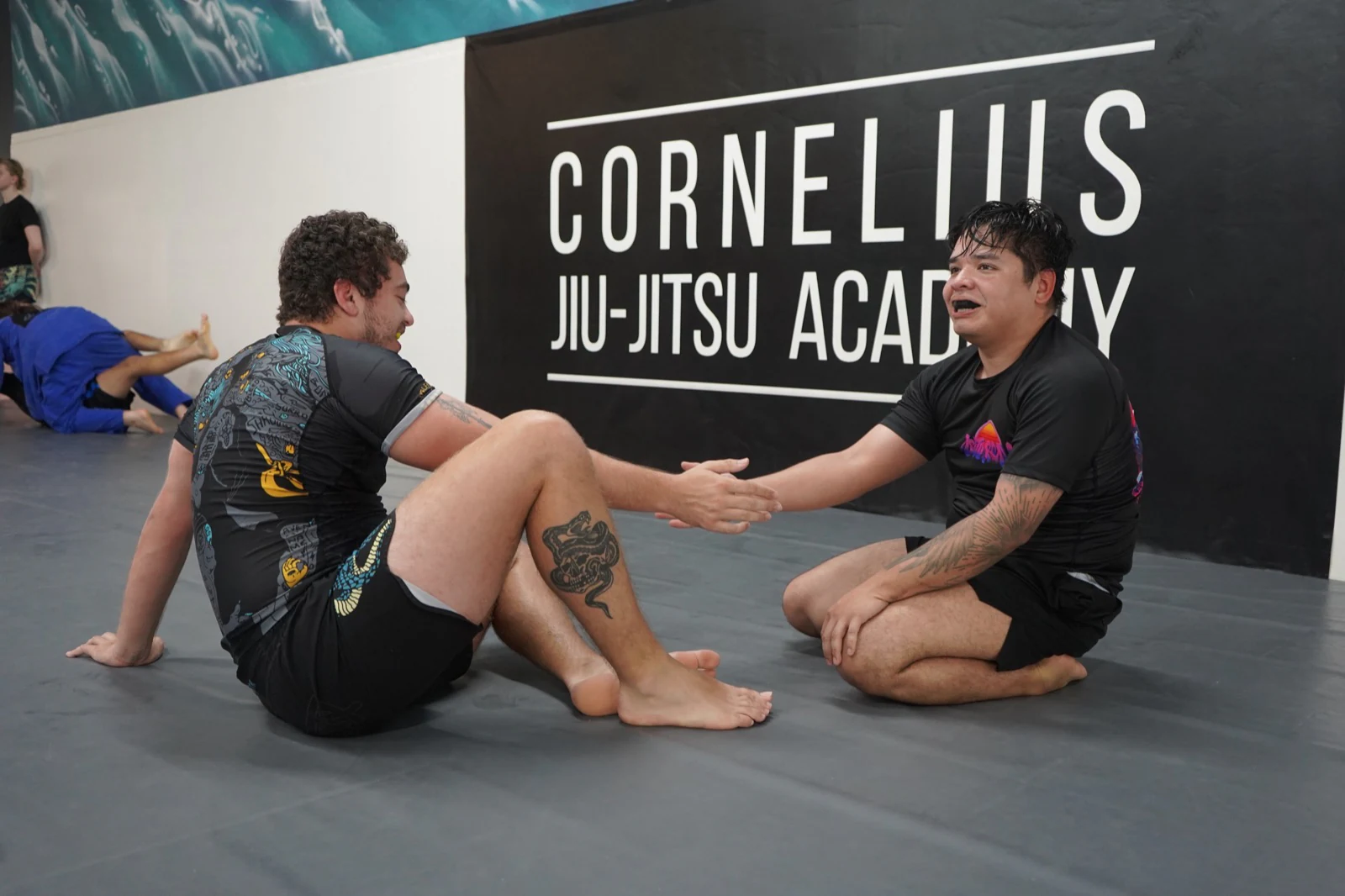 Two training partners shaking hands in front of the CJJA banner